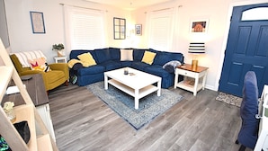 A living room with a blue sofa, a white coffee table, and a ceiling fan. - Extra Entertainment Space Just 7 Blocks to ND Campus 54211 (Mishawaka)