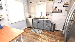 A modern kitchen with wooden flooring, a sink, cabinets, and a refrigerator. - Extra Entertainment Space Just 7 Blocks to ND Campus 54211 (Mishawaka)