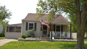 A single-story house with a front porch, a small garden with purple flowers, and an American flag. - Extra Entertainment Space Just 7 Blocks to ND Campus 54211 (Mishawaka)