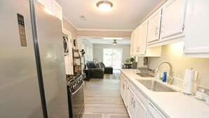 Una cocina moderna con armarios blancos, electrodomésticos de acero inoxidable y una isla central.