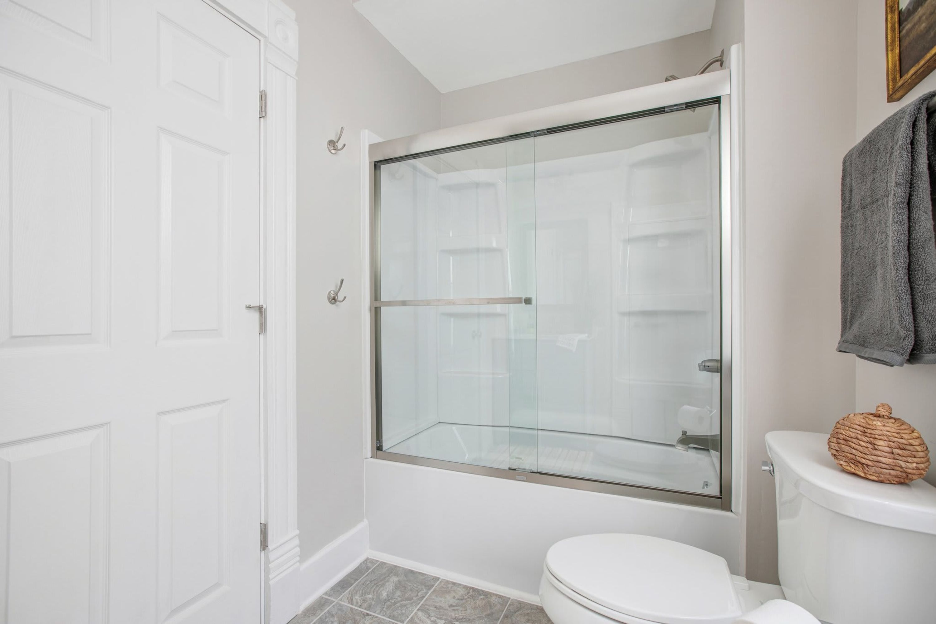 A bathroom with a glass-enclosed shower, a white toilet, and a towel rack with a towel.