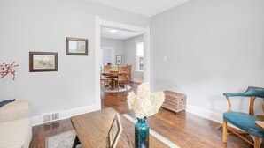 A spacious living room with a wooden dining table, a blue vase with white flowers, and a blue chair. - 3 Bedroom 2 Bath Home Near Notre Dame 123nd (South Bend)
