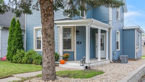 A two-story house with a covered porch, a small garden with a tree and a pumpkin, and a gravel driveway. - 3 Bedroom 2 Bath Home Near Notre Dame 123nd (South Bend)