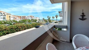 Un balcone con vista su una zona residenziale, una sedia bianca e un tavolino.