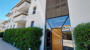 Un edificio moderno con facciata bianca, ampie finestre e una porta in legno.