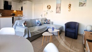 Un soggiorno moderno con un divano, un tavolino da caffè e una poltrona. C'è una zona cucina con mobili e un piano di lavoro.