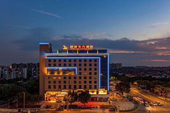 Un hotel de varios pisos con un diseño moderno, que cuenta con una entrada destacada y una terraza en la azotea.