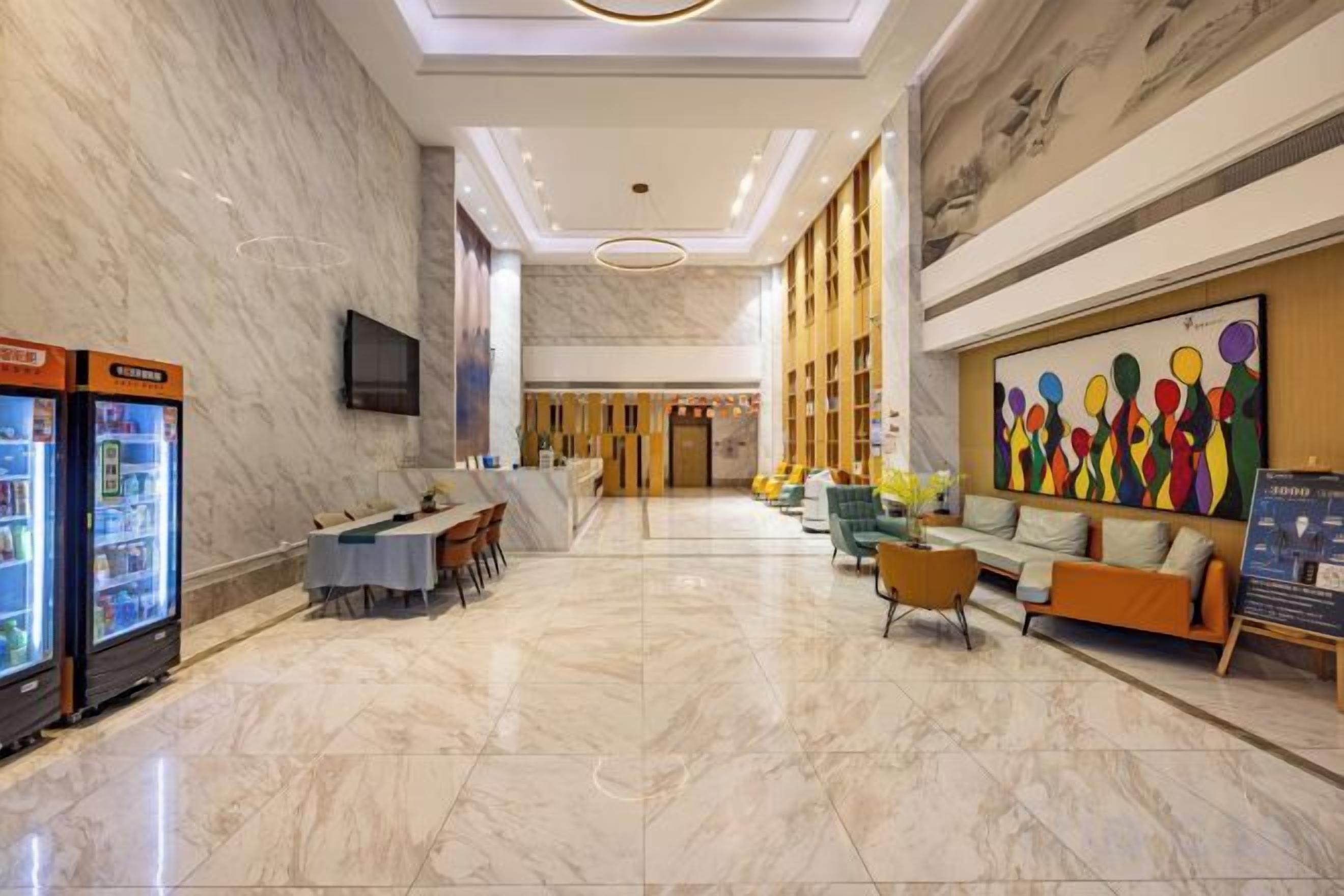 Un hall d’hôtel doté d’un sol en marbre, d’un comptoir de réception, d’un espace salon et d’une grande œuvre d’art accrochée au mur.