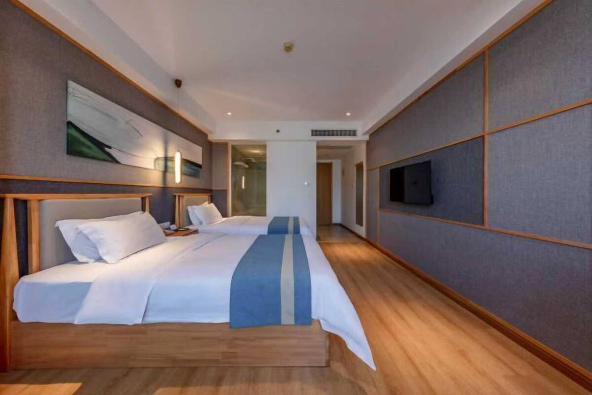 A hotel room with a large bed, bedside tables, a flat-screen TV, and a painting on the wall.