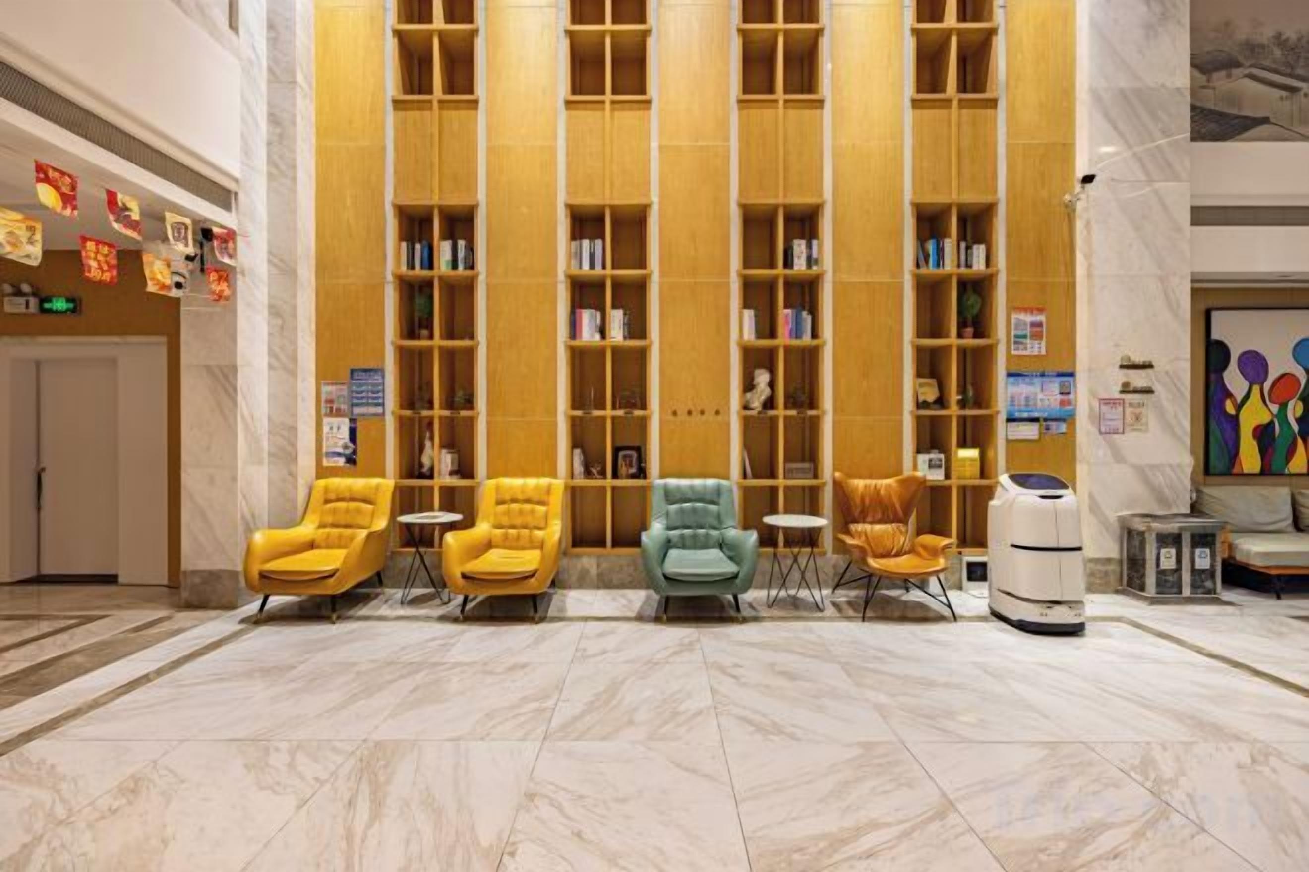 Un vestíbulo con piso de mármol, una hilera de estanterías y cuatro sillones.