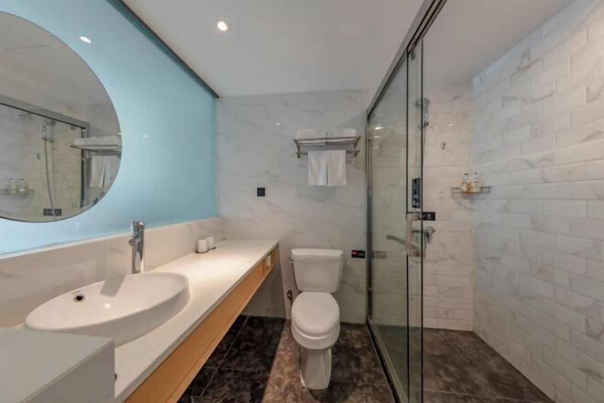 A modern bathroom with a white sink, a toilet, and a glass-enclosed shower.