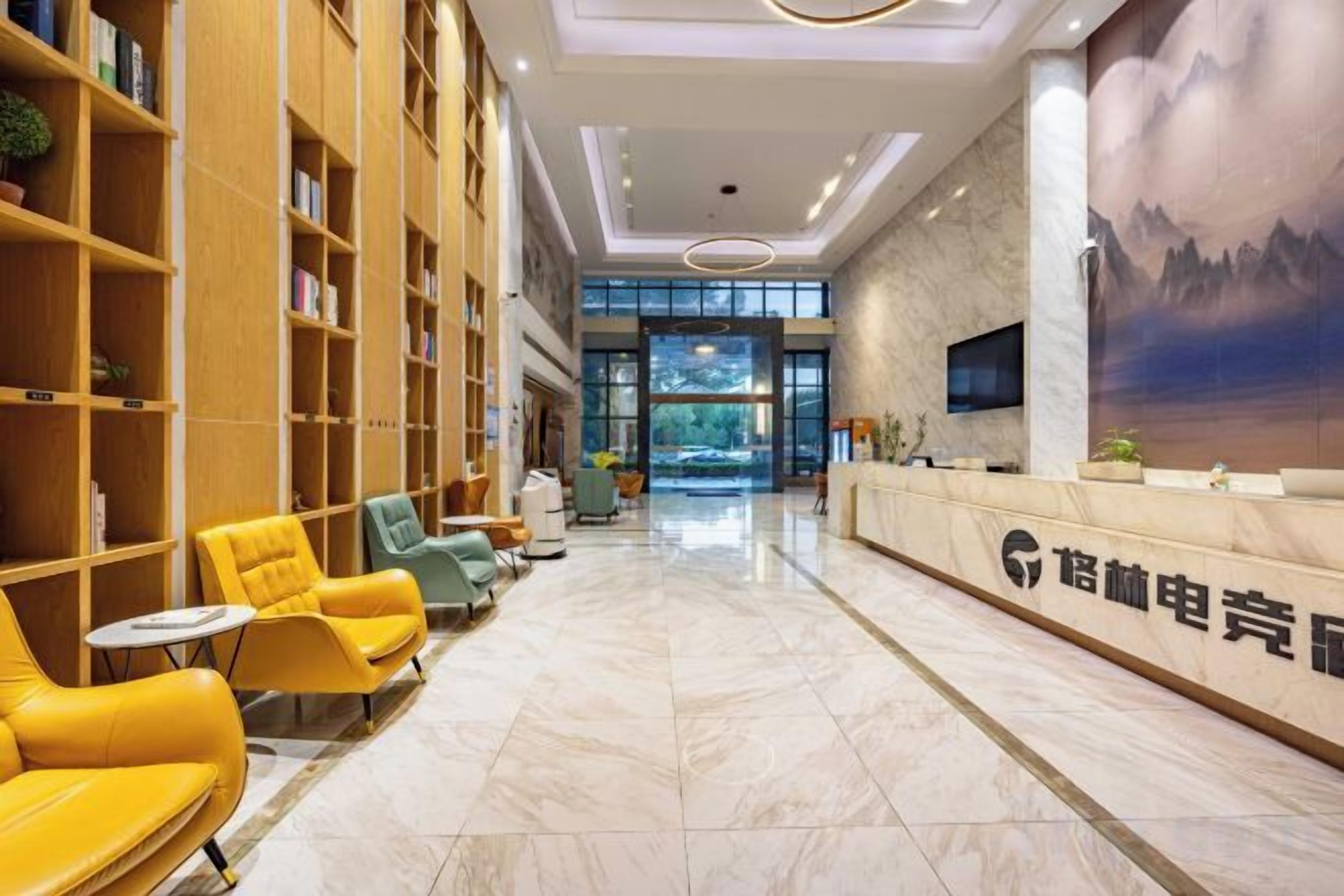 A hotel lobby with a reception desk, seating area, and bookshelves.
