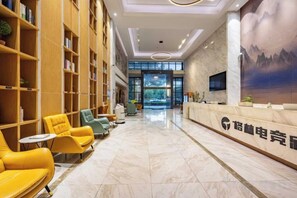 Un hall d’hôtel comprenant un comptoir d’accueil, un espace salon et des étagères à livres.