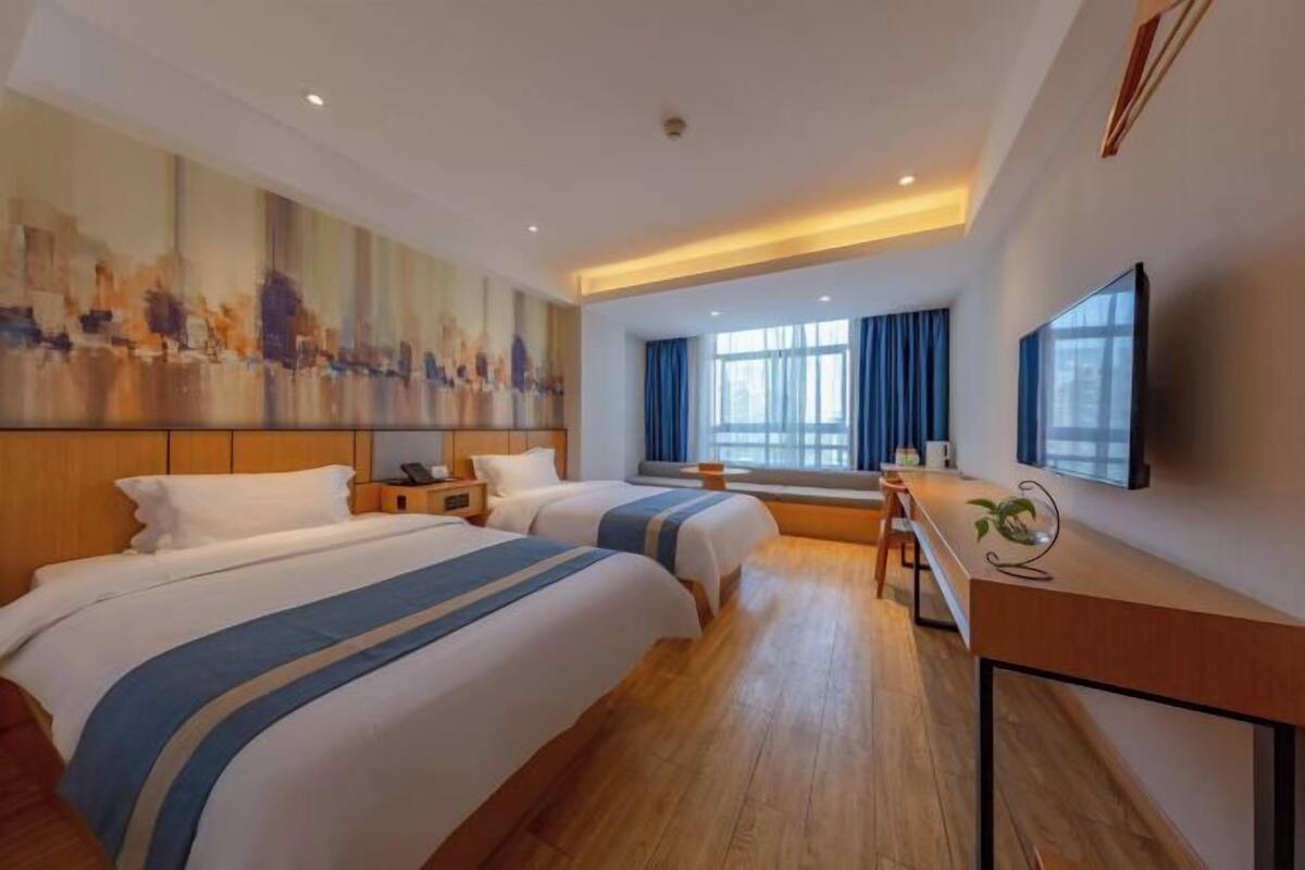 A hotel room with two beds, a desk, a large painting, and a TV.