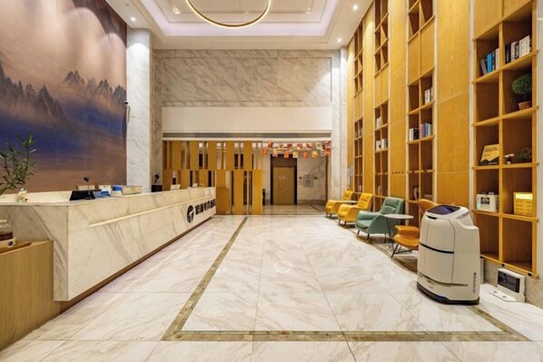 Un hall d’hôtel comprenant un comptoir d’accueil, un espace salon et des étagères à livres.