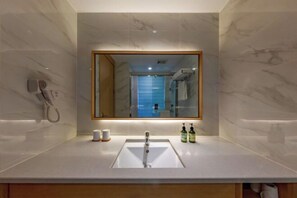 A modern bathroom with a marble wall, a large mirror, a sink, and a hairdryer on the left. - Greentree Eastern Hotel (Zhongshan West Road, Xiuzhou District, Jiaxing) (Jiaxing)