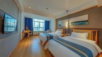 Een hotelkamer met twee bedden, een bureau en een groot raam.
