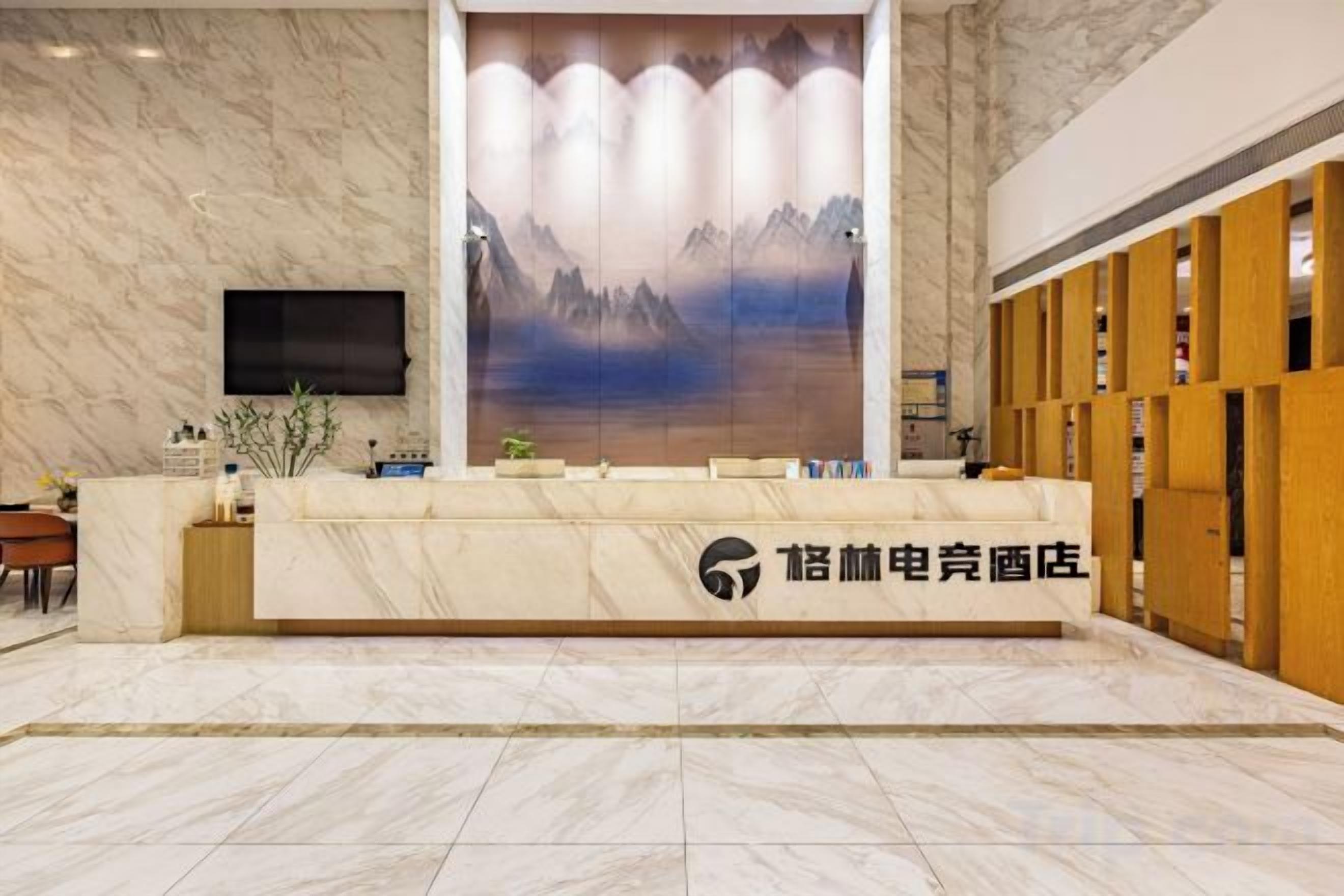 A hotel reception area with a marble reception desk, a large wall-mounted screen, and a wooden panel wall.