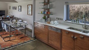 A modern kitchen with a skylight, wooden cabinets, and a dining area with a glass table and chairs. -  Well equipped lodge,  Next to Holkham Hall and villages close to the Beach  (Holkham wells by the sea)