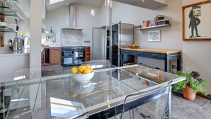 A modern kitchen with a glass dining table, a built-in oven, and a refrigerator. -  Well equipped lodge,  Next to Holkham Hall and villages close to the Beach  (Holkham wells by the sea)