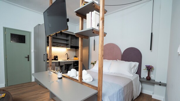 A modern hotel room with a bed, a desk, and a kitchenette. - Modern & Sunny apartment with Garden View in the heart of the city center NYX 1 (Tripoli)