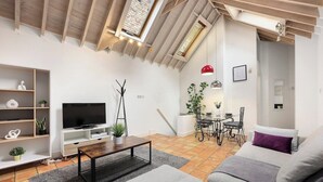 A modern living room with a TV, sofa, coffee table, and a dining area with a table and chairs. - Cozy private 1-bedroom apartment in Hoxton (Greater London)