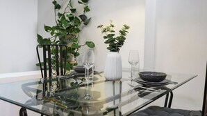 A modern dining area with a glass table, metal chairs, a white vase, and a potted plant. - Cozy private 1-bedroom apartment in Hoxton (Greater London)