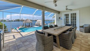 Ein überdachter Außenbereich mit Pool, Korbmöbeln und Meerblick.