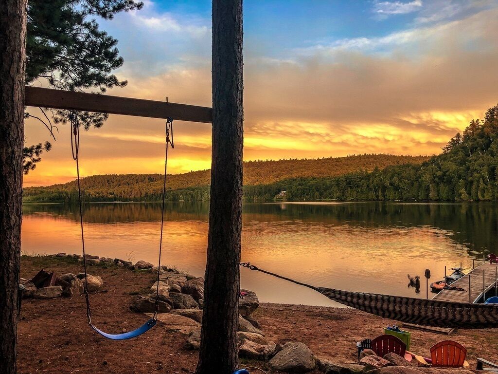 A lakeside view with a hammock, dock, and dock chairs.