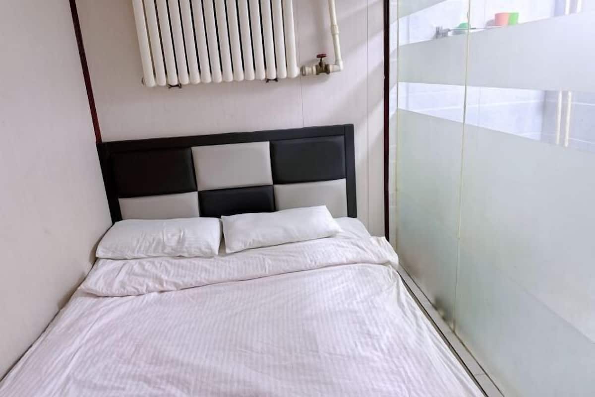 A bed with white bedding, a black and white headboard, and a radiator above it.