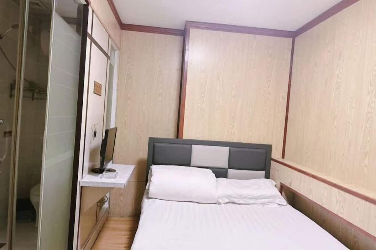 A bedroom with a bed, a bedside table, a mirror, and a wardrobe.