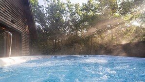 Un jacuzzi rodeado de árboles, con vapor elevándose del agua.