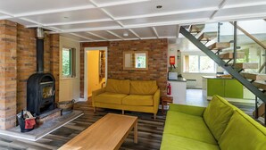 Una sala moderna con chimenea de ladrillo, un sofá amarillo, un sofá verde y una mesa de madera.