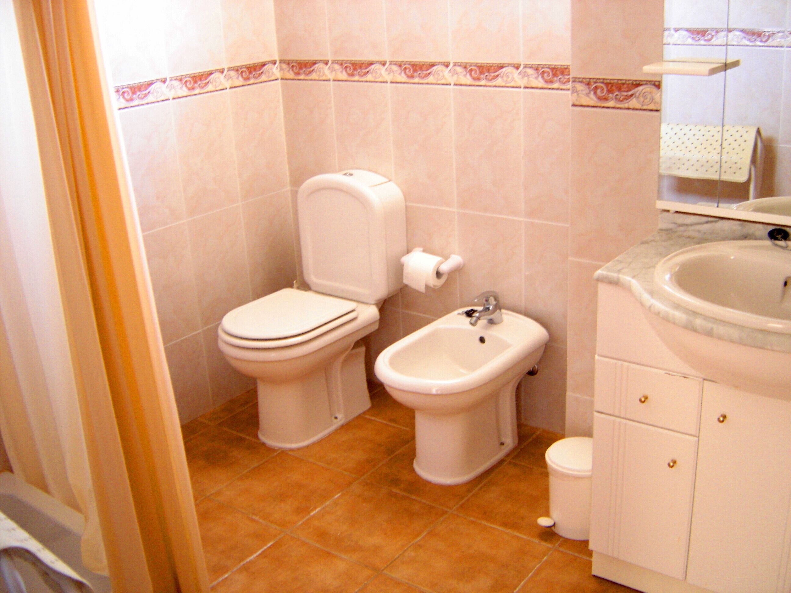 A bathroom with a toilet, bidet, and sink.