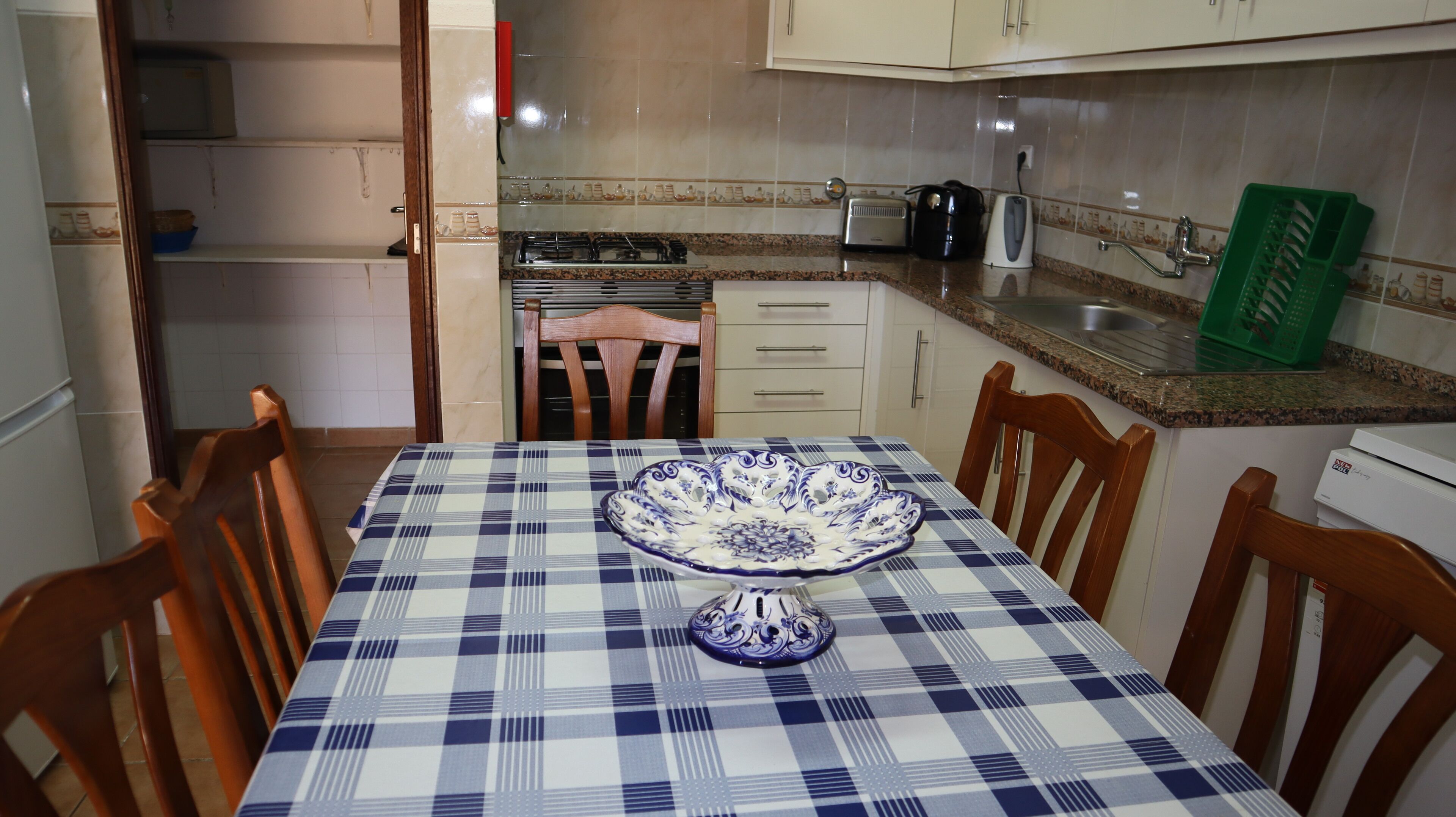 A dining area with a checkered tablecloth, a decorative plate, and wooden chairs.