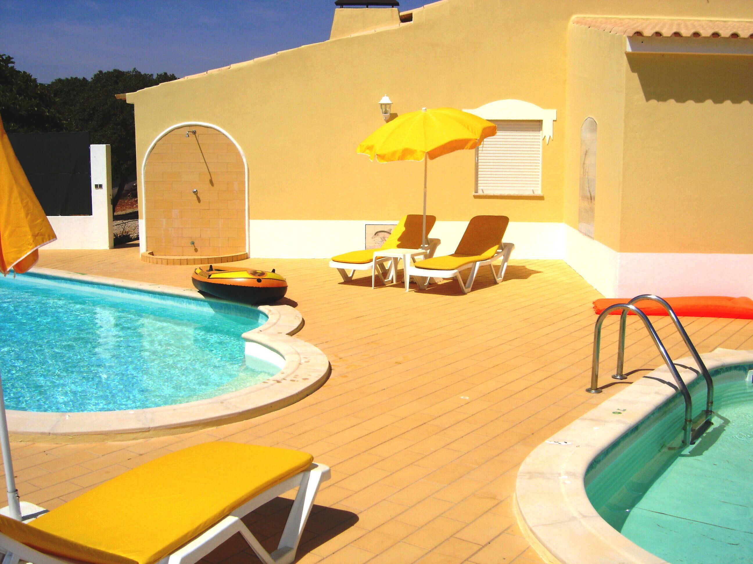 A pool area with a hot tub, lounge chairs, and an inflatable raft.
