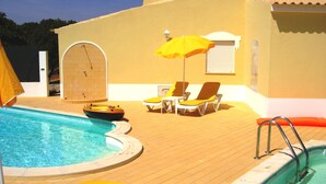 Un espace piscine comprenant un jacuzzi, des chaises longues et un radeau gonflable.
