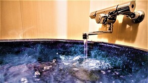 A bathtub with running water, a faucet, and a wall-mounted control.