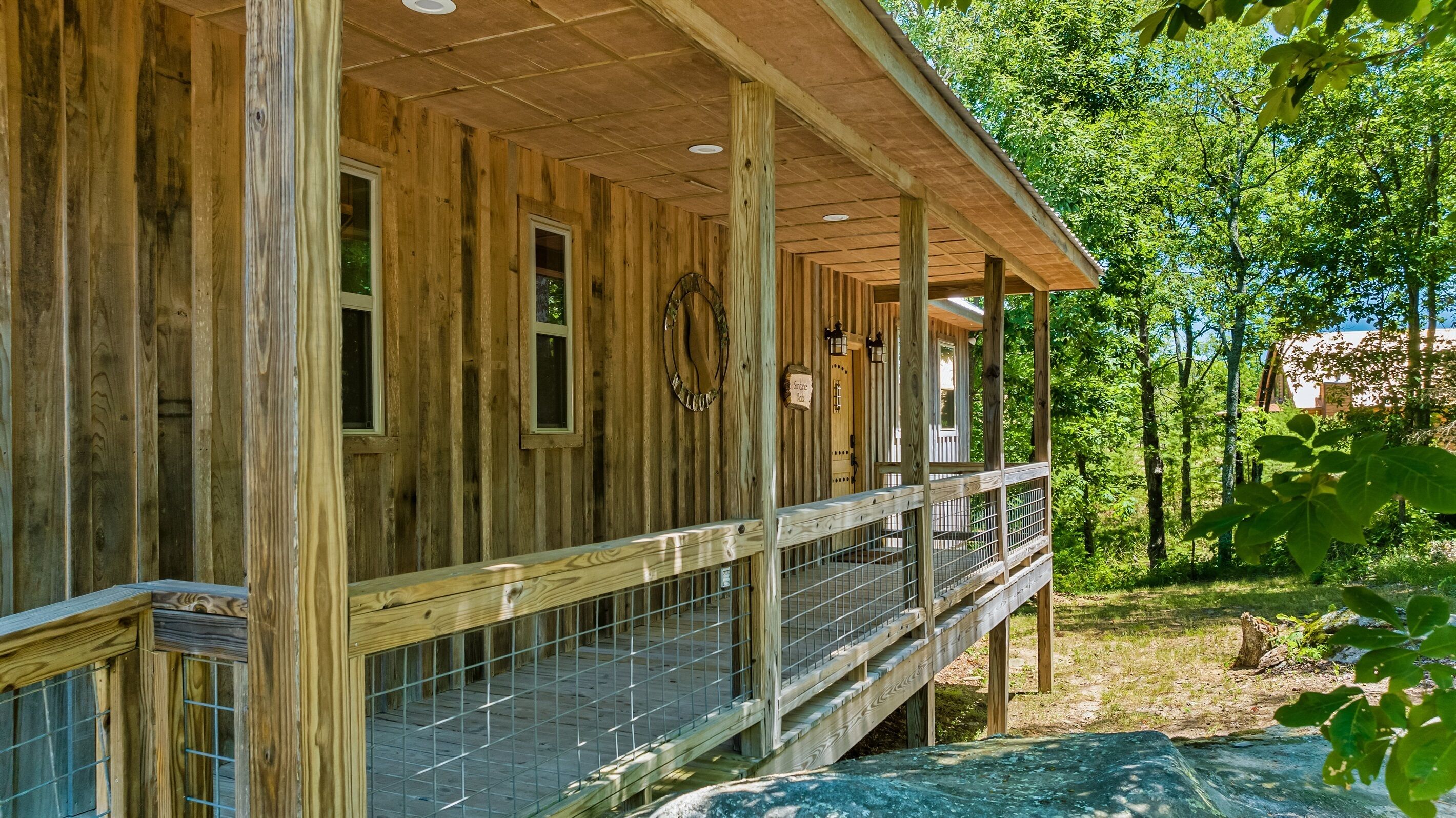 A wooden cabin with a covered porch and a fenced deck.