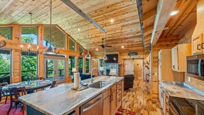 Ein Holzblock-Interieur mit Küche, Essbereich und großen Fenstern.