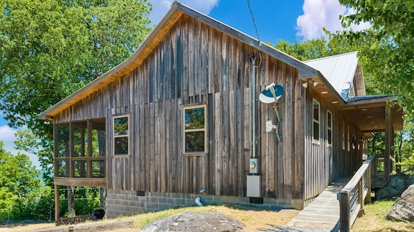 A rustic wooden building with large windows, a porch, and a satellite dish.