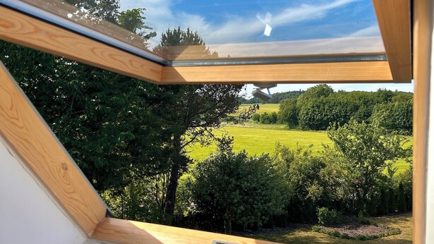A skylight with a view of a green landscape and trees. - Apartamenty Golf Dyndeby (Nexø)