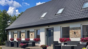 A modern house with a sloped roof, large windows, and a paved driveway. - Apartamenty Golf Dyndeby (Nexø)