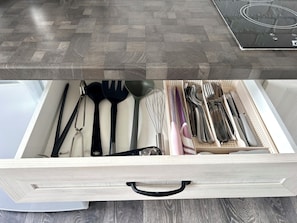 Un cajón con utensilios de cocina ordenados, incluyendo espátulas, batidores y cuchillos.
