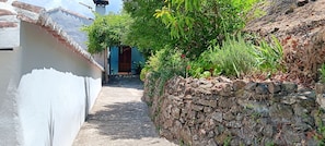 A narrow alleyway with a stone wall on one side and a white building on the other. - Country Rental Home Genalguacil Jubrique. Hiking, Biking, Nature, White Villages (Jubrique)