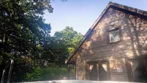 A wooden cabin with a hot tub in front. - Denstone; woodland lodge for 8 with hot tub, log burner, BBQ, near Alton Towers. (Stoke-on-Trent)