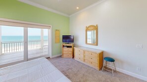 Une chambre à coucher avec un lit, une commode, un téléviseur et un miroir.
