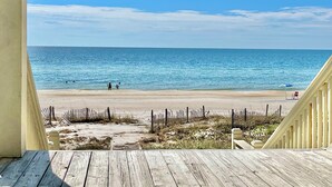 Eine Holzterrasse mit Blick auf Strand und Meer.