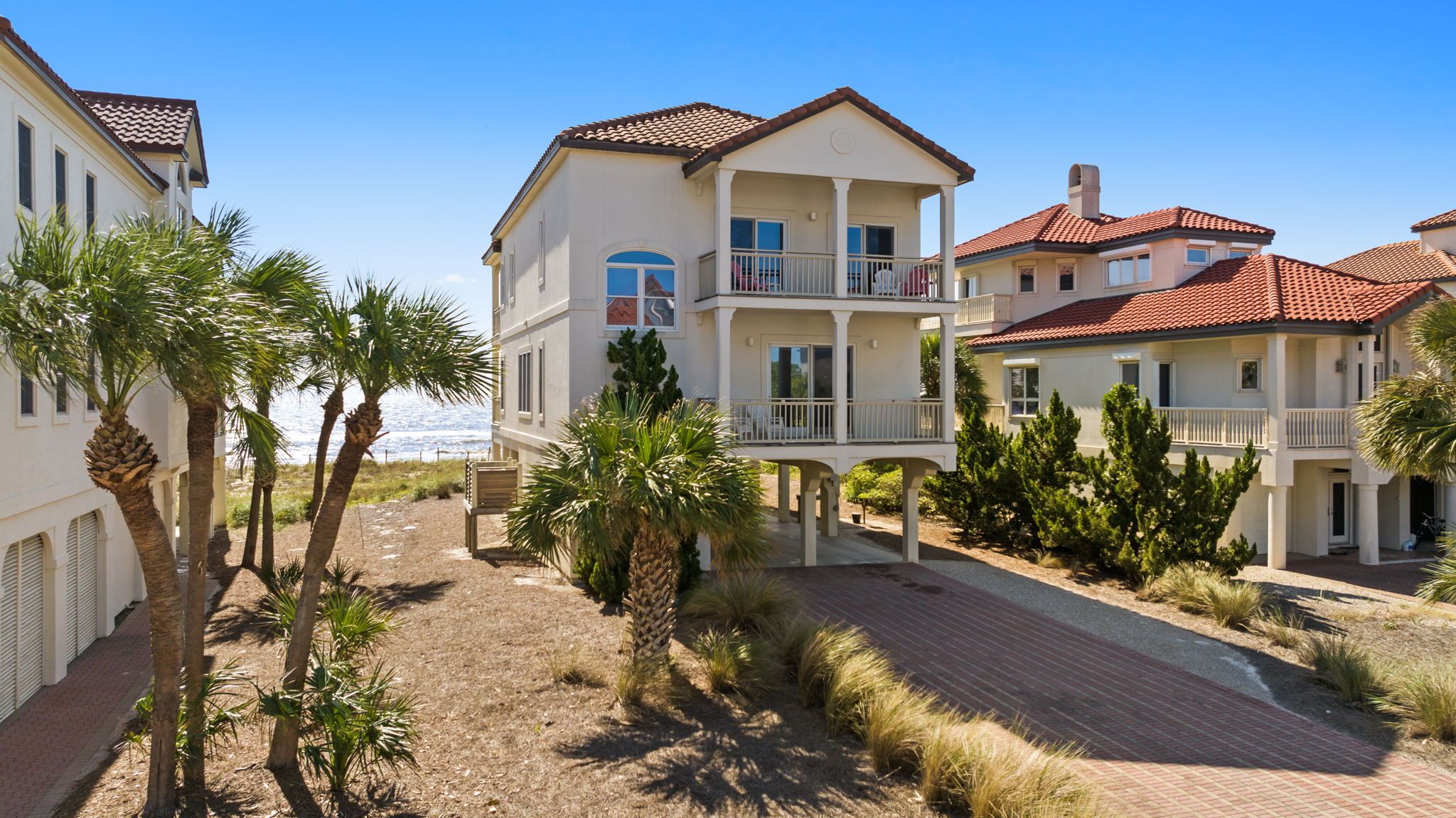 A multi-story residential building with balconies, a paved driveway, and surrounding vegetation.