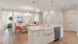 A modern kitchen with white cabinetry, a central island, and pendant lighting. - Executive  style home with 4 bedrooms and 3.5 baths. (Saint Simons Island)